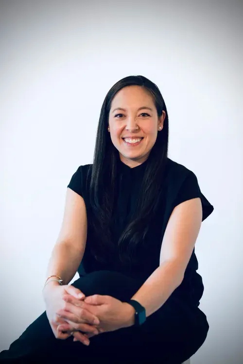 A woman sitting on the ground smiling for the camera.